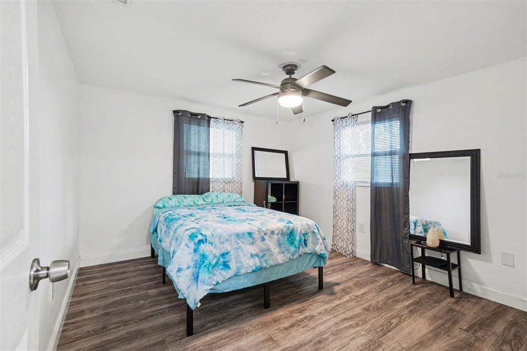11828 Bingham Drive Port Richey, FL 34668 - Photo 20 of 32 a bedroom with a large bed a chandelier and dresser
