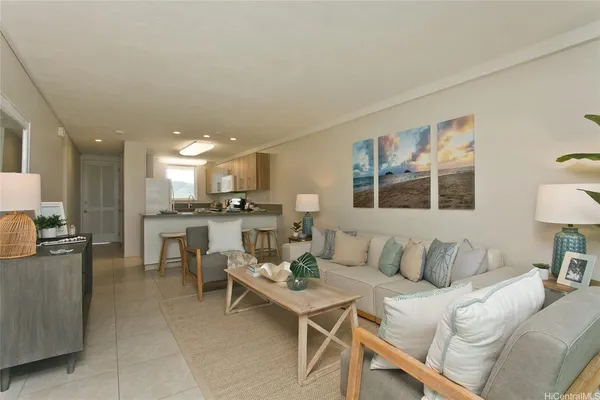 a living room with stainless steel appliances furniture a rug and a kitchen view