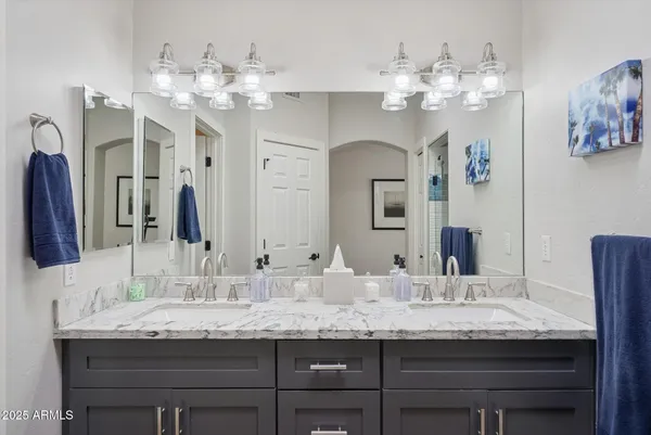 a bathroom with a granite countertop double vanity sink and a mirror