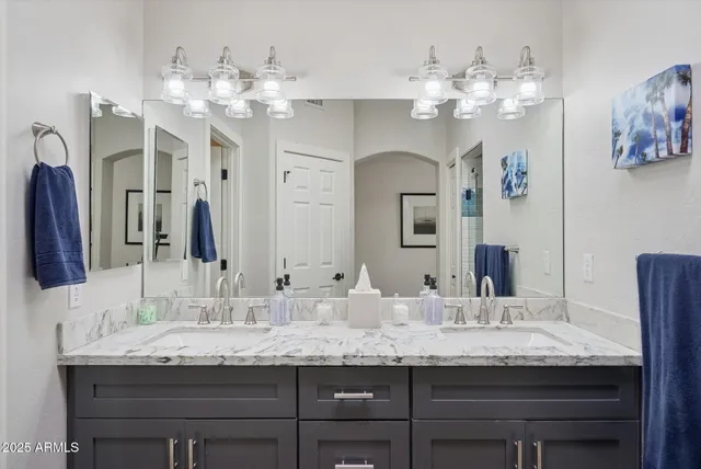 a bathroom with a granite countertop double vanity sink and a mirror