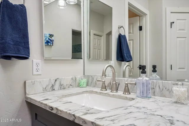 a bathroom with a granite countertop sink and a mirror