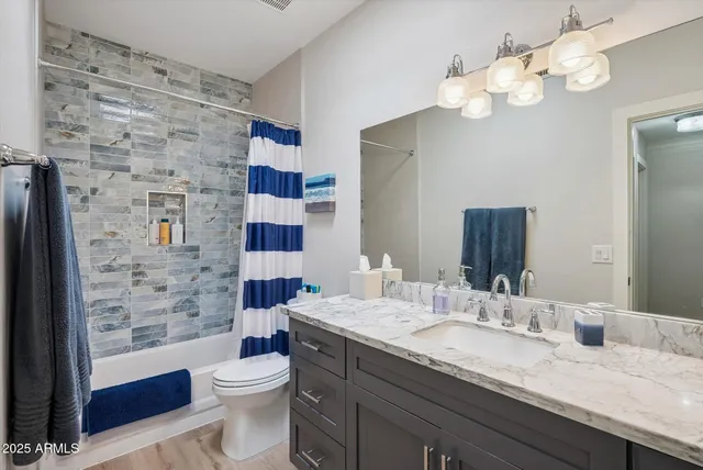 a bathroom with a granite countertop toilet sink and mirror
