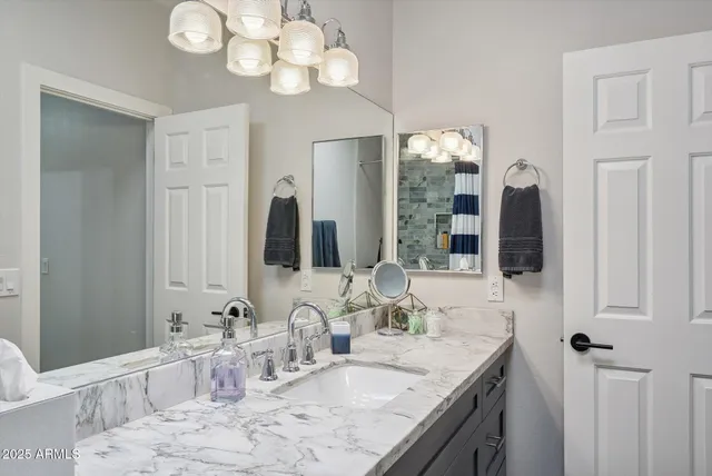 a bathroom with a granite countertop sink a large mirror and a shower