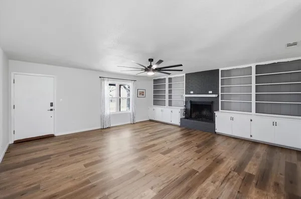 a view of empty room with wooden floor and fireplace