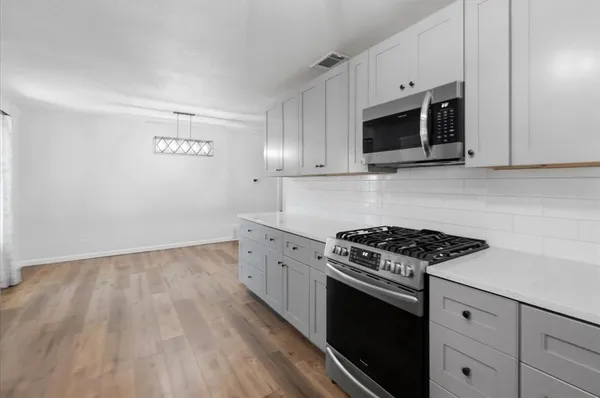 a kitchen with granite countertop white cabinets and black appliances