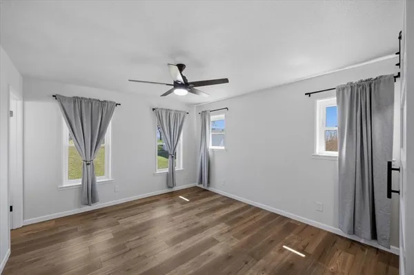 a view of empty room with wooden floor and window