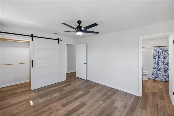 an empty room with wooden floor closet fan and windows