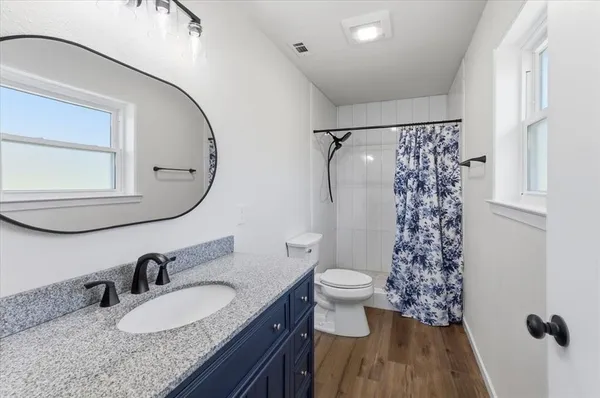 a bathroom with a granite countertop sink a toilet and a mirror