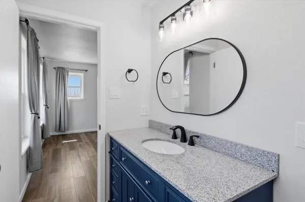 a bathroom with a granite countertop sink a mirror and shower view