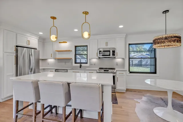 a large kitchen with stainless steel appliances granite countertop a stove a refrigerator a oven a sink with a dining table and chairs