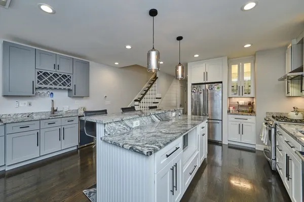 a kitchen with stainless steel appliances kitchen island granite countertop a refrigerator a stove a sink and white cabinets