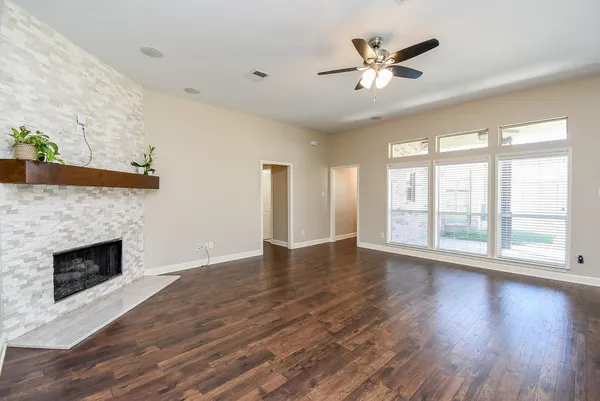 an empty room with wooden floor fireplace and windows