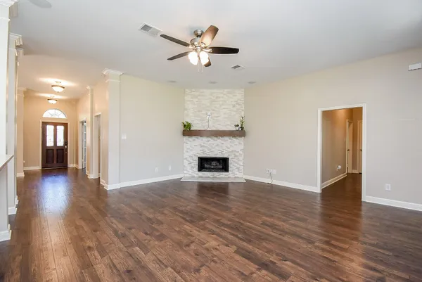 a view of a livingroom with wooden floor a ceiling fan and a window