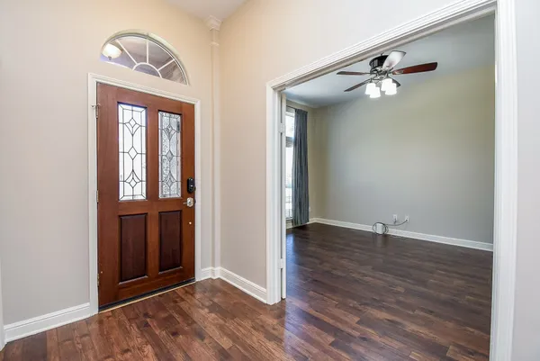 an empty room with wooden floor cabinet and windows
