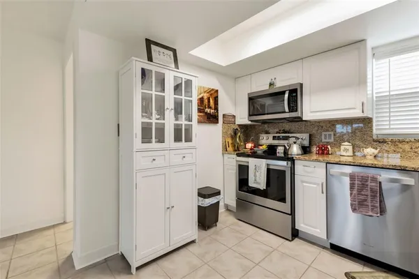 a kitchen with stainless steel appliances granite countertop a refrigerator a stove a sink and a microwave