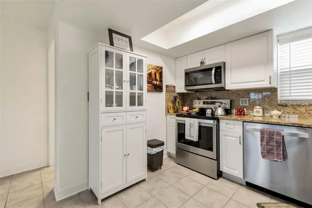 a kitchen with stainless steel appliances granite countertop a refrigerator a stove a sink and a microwave