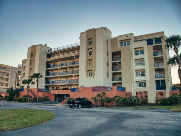 a front view of a building with lot of cars and trees