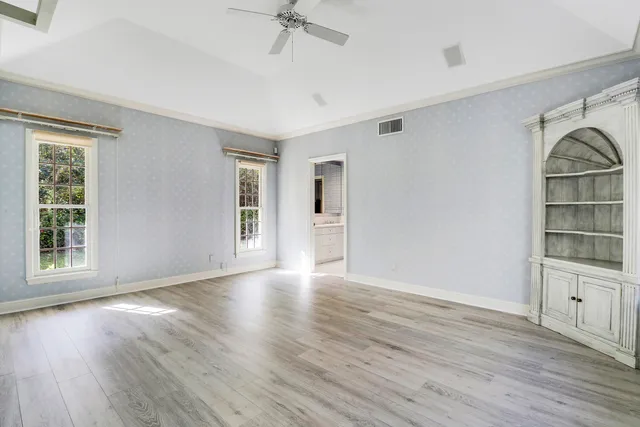a view of an empty room with a window and wooden floor
