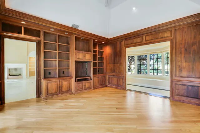 a view of an empty room with a fireplace and wooden floor