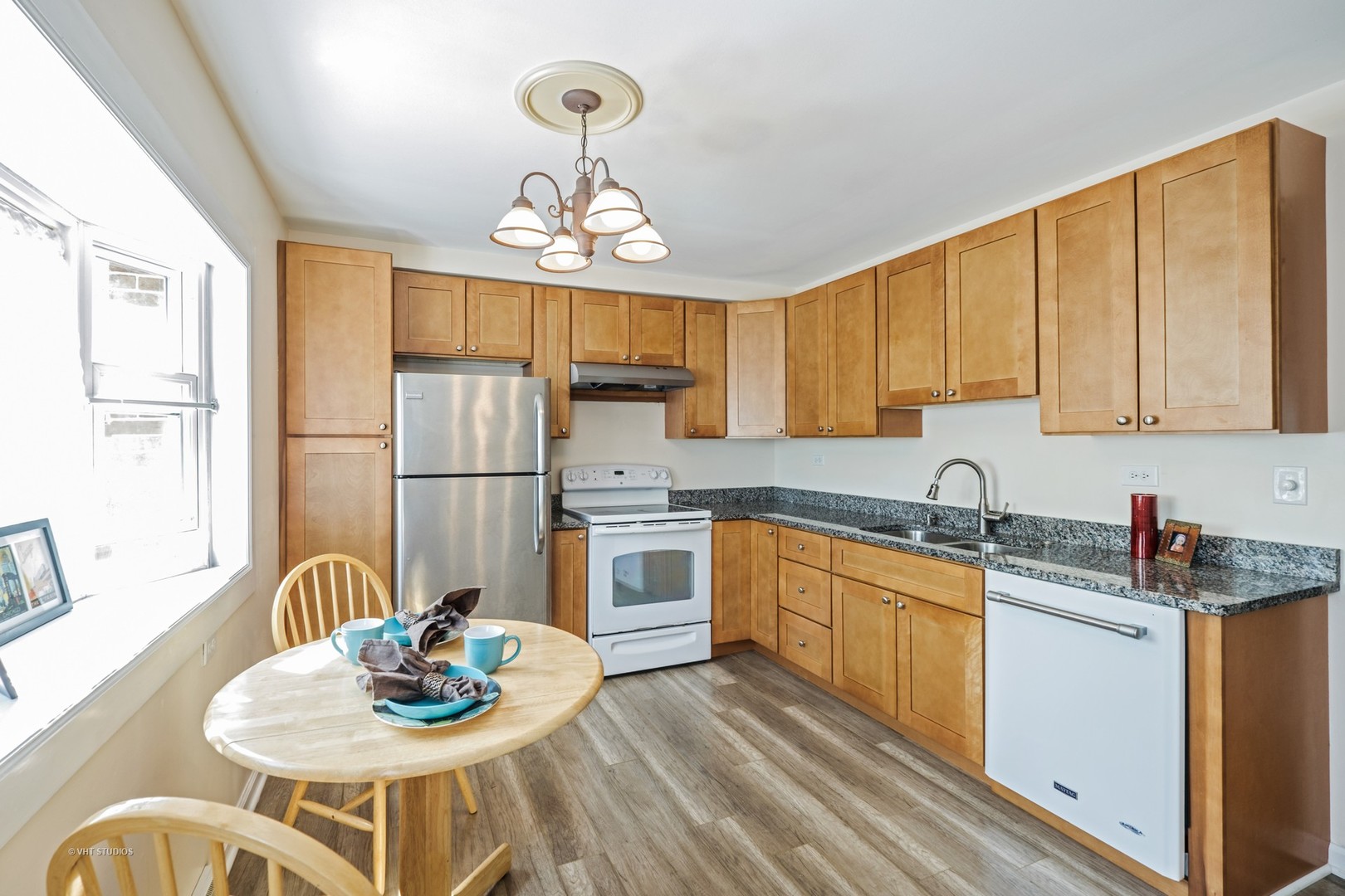 314 Skokie Road Wilmette, IL 60091 - Photo 4 of 14 a kitchen with stainless steel appliances granite countertop wooden floor white cabinets dining table and chairs