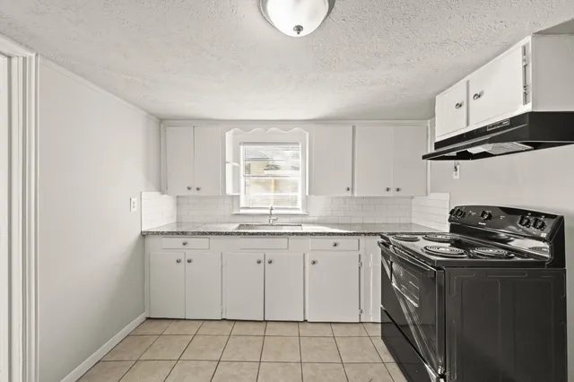 a kitchen with granite countertop a stove sink and cabinets