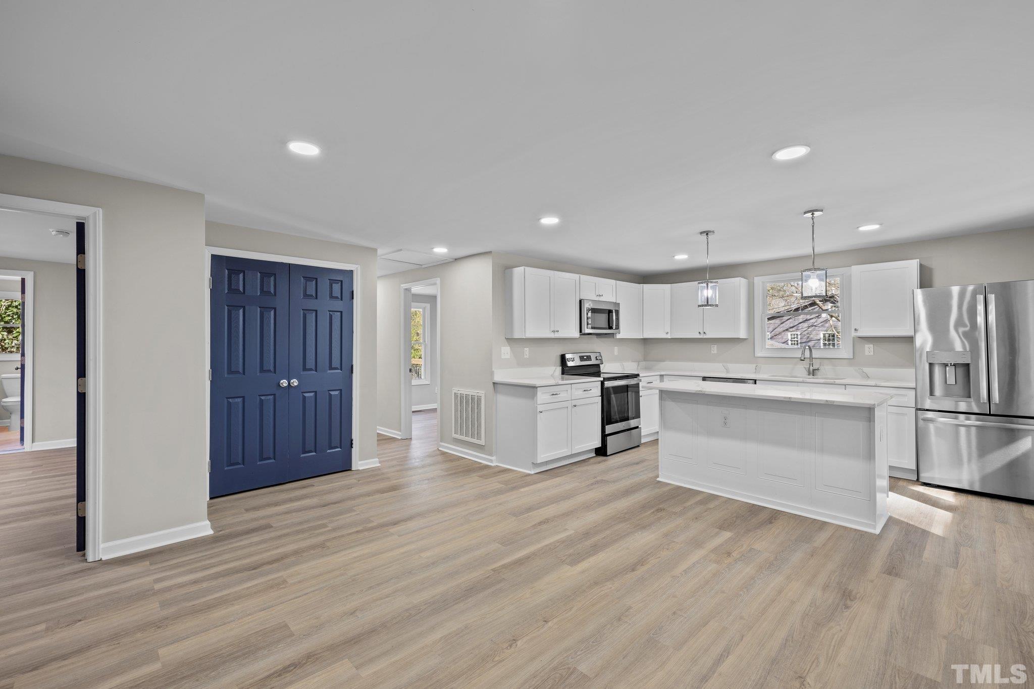 2908 Woods Place Raleigh, NC 27607 - Photo 21 of 38 a kitchen with white cabinets and stainless steel appliances