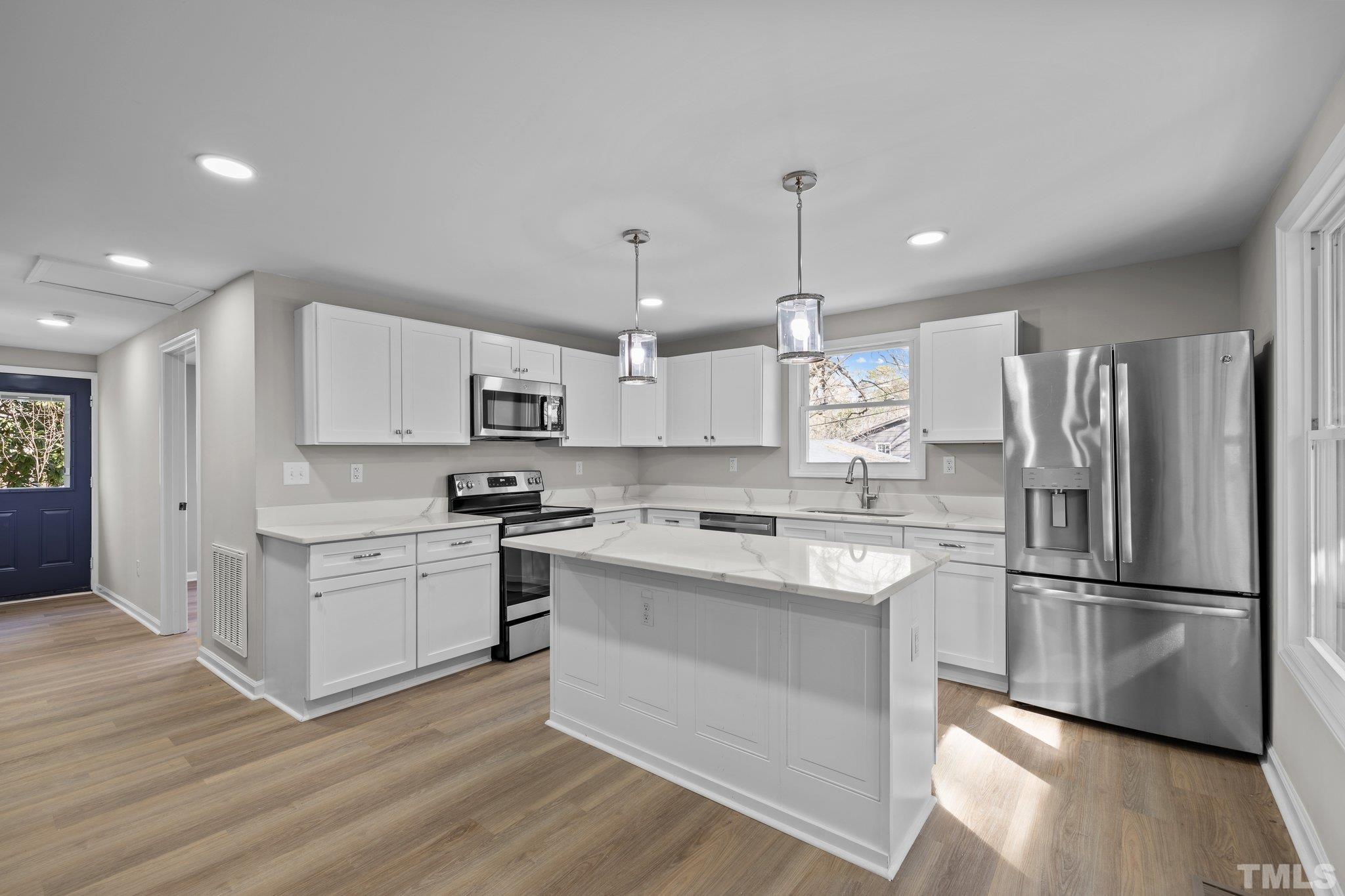 2908 Woods Place Raleigh, NC 27607 - Photo 24 of 38 a kitchen with stainless steel appliances granite countertop a refrigerator a stove a sink dishwasher and white cabinets with wooden floor