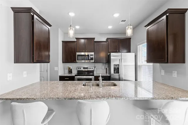 a kitchen with stainless steel appliances granite countertop a sink and a refrigerator