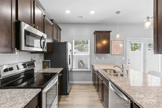 a kitchen with stainless steel appliances granite countertop a stove a sink and a refrigerator