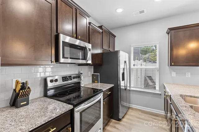 a kitchen with granite countertop a stove top oven a sink a counter space and cabinets