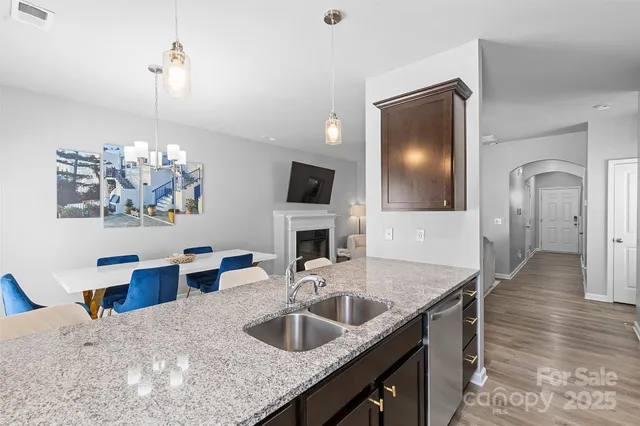 a kitchen view with granite countertop a sink dishwasher a dining table and chairs with wooden floor