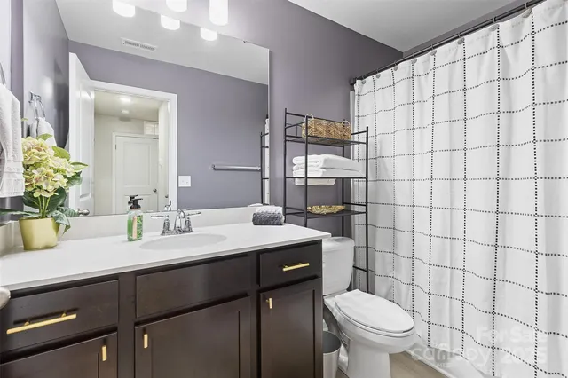 a bathroom with a granite countertop sink toilet and mirror