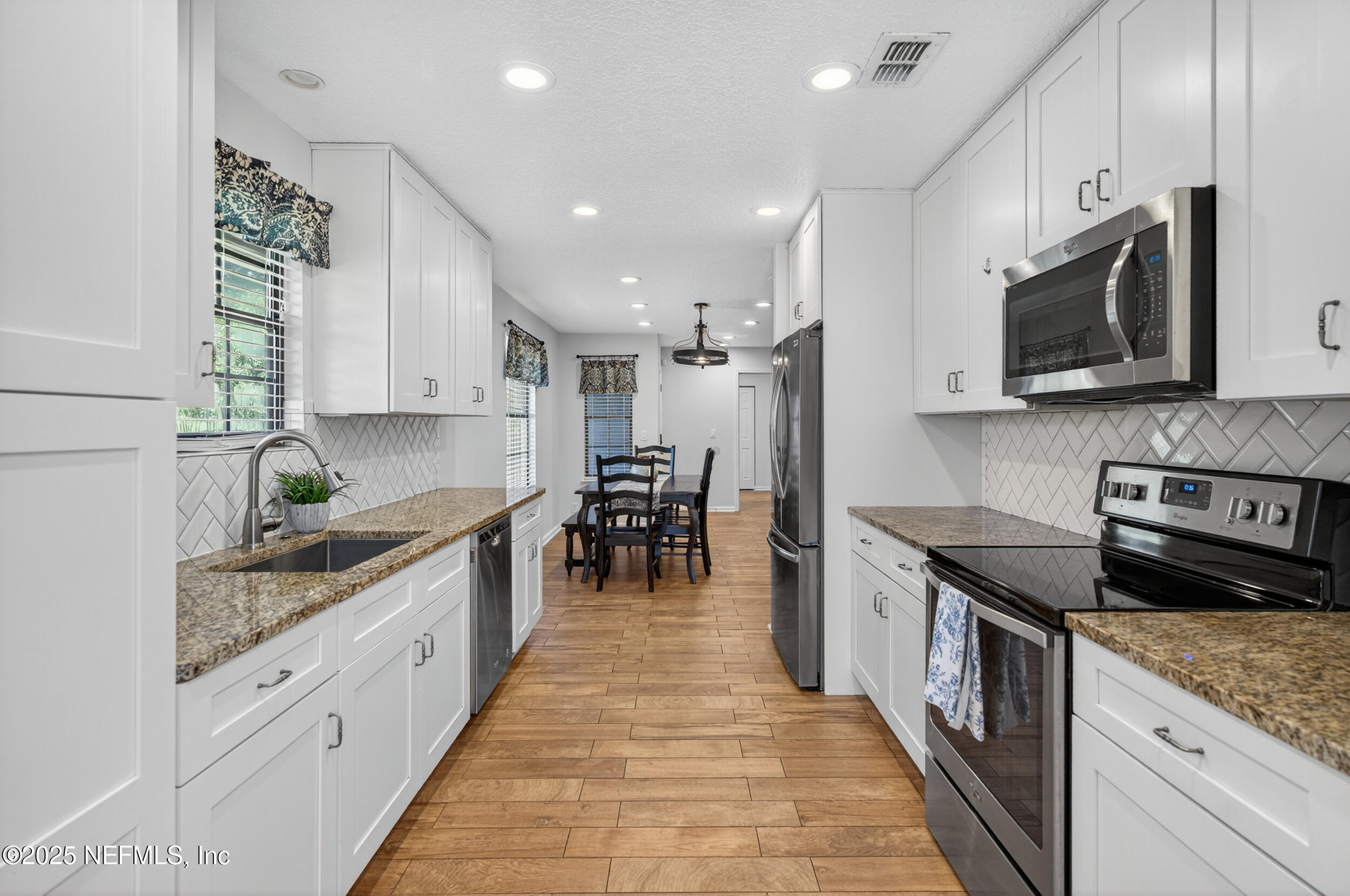 2836 Eagle Point Road Middleburg, FL 32068 - Photo 12 of 44 a kitchen with stainless steel appliances granite countertop a stove top oven a sink a dining table and chairs