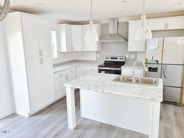 a kitchen with stainless steel appliances granite countertop a sink stove a refrigerator and white cabinets with wooden floor