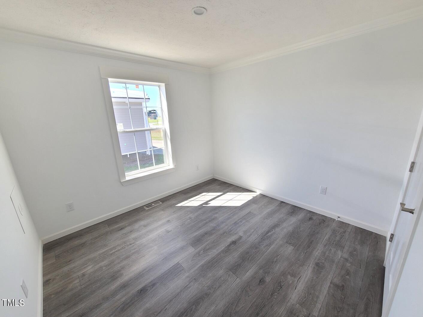 1398 Earpsboro Road Zebulon, NC 27597 - Photo 8 of 14 an empty room with wooden floor and windows