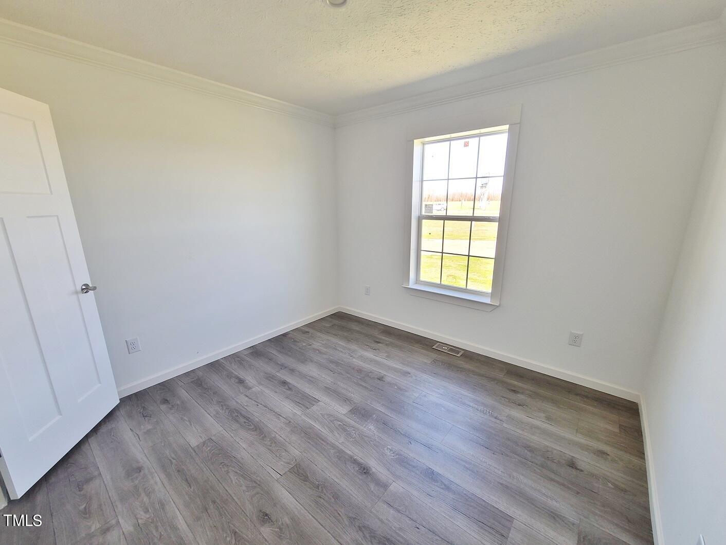 1398 Earpsboro Road Zebulon, NC 27597 - Photo 10 of 14 an empty room with wooden floor and windows