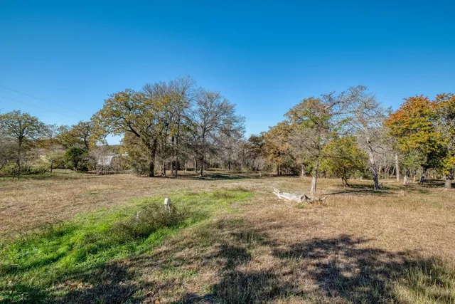 a view of dirt field with trees in the background