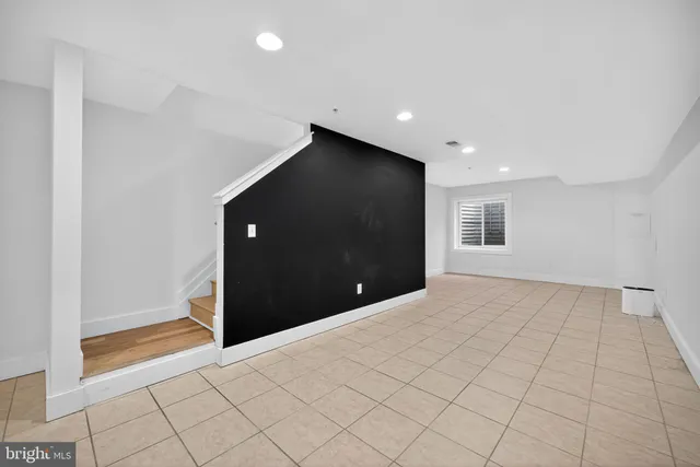 a view of an empty room with window and stairs