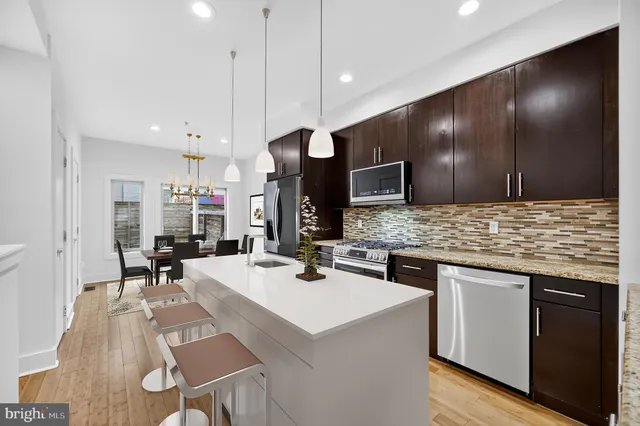 a kitchen with a stove a refrigerator and chairs