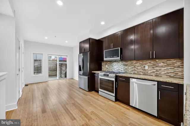 a kitchen with stainless steel appliances granite countertop a stove and a wooden floors