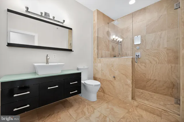 a bathroom with a toilet a sink a mirror and shower