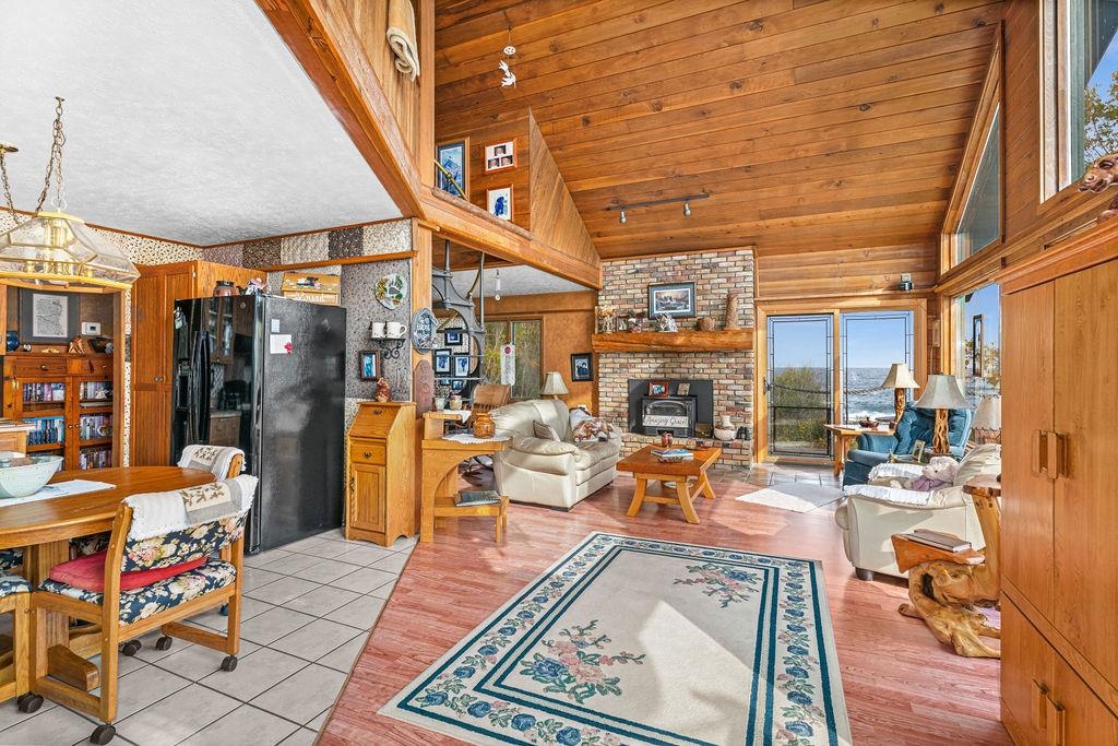 4346 Highway 61 Two Harbors, MN 55616 - Photo 36 of 65 Living room with high vaulted ceiling, wood walls, a wood stove, light wood finished floors, and wood ceiling