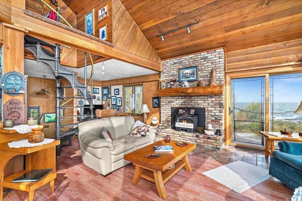 4346 Highway 61 Two Harbors, MN 55616 - Photo 39 of 65 Living area with a wood stove, wood finished floors, high vaulted ceiling, wooden walls, and wooden ceiling