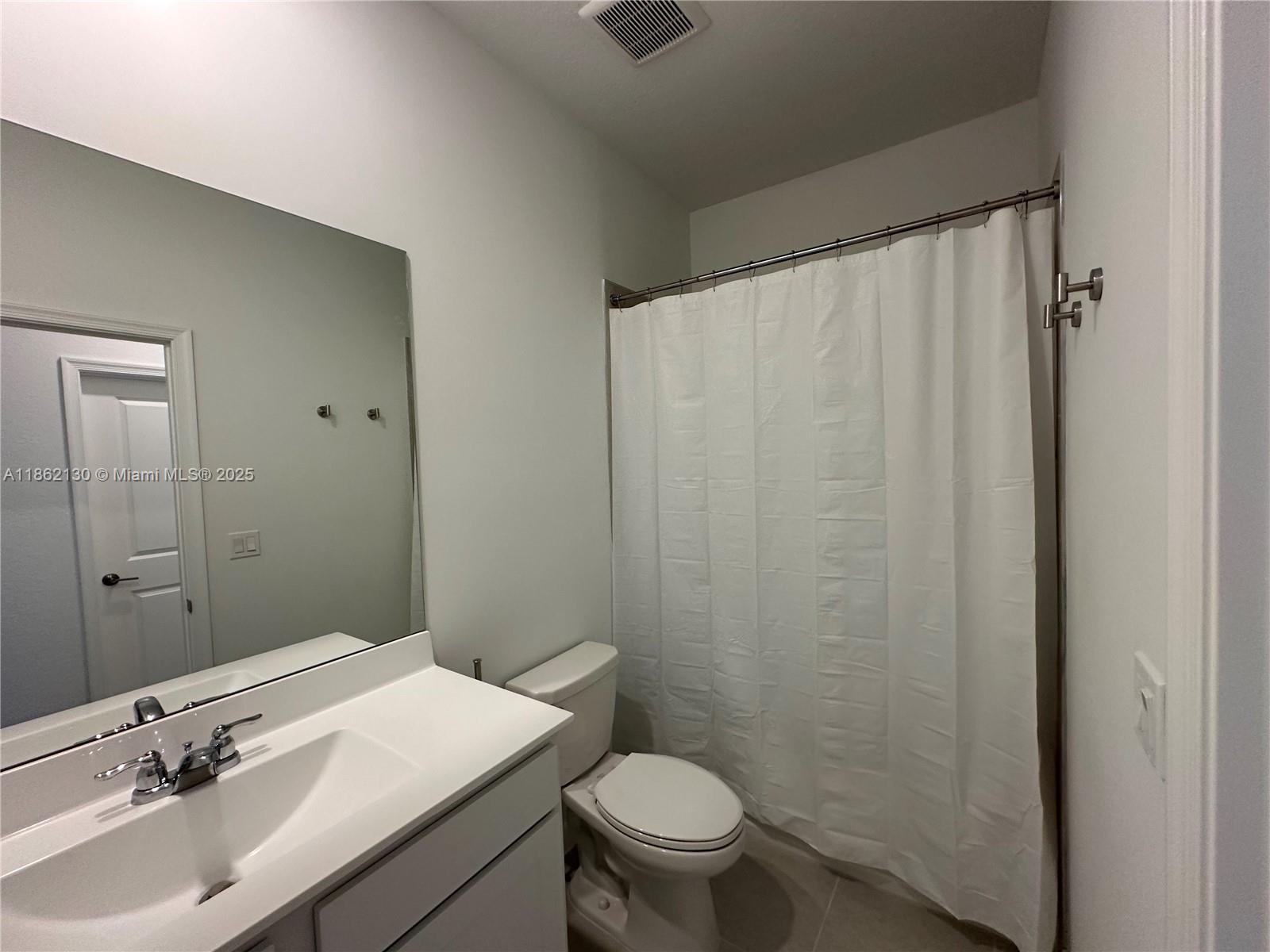 402 Southeast Crossoak Lane, Unit 402 Port St. Lucie, FL 34984 - Photo 54 of 87 a bathroom with a sink a toilet and shower curtain