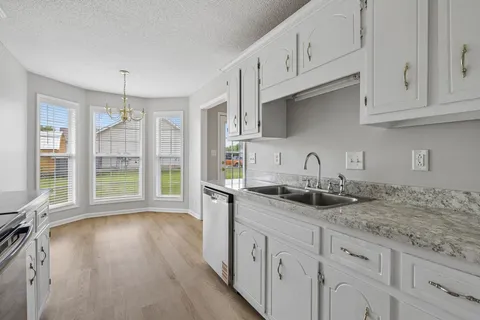 a kitchen with granite countertop a sink a stove and refrigerator