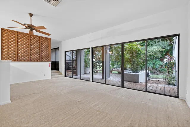 an empty room with windows and ceiling fan