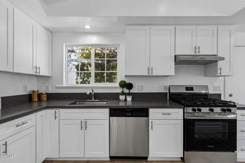a kitchen with stainless steel appliances granite countertop white cabinets and a stove a sink
