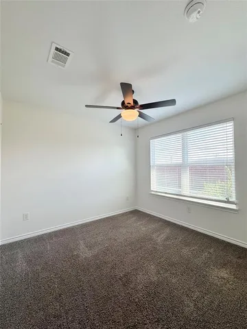 an empty room with windows and fan