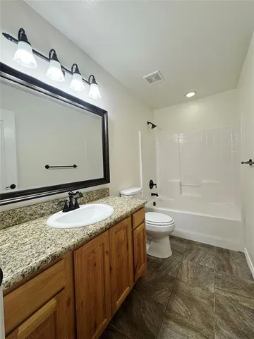 a bathroom with a granite countertop sink mirror and a toilet