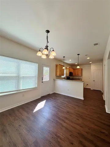 a view of a room with a chandelier and wooden floor